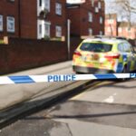 Image of police car and police cordon on UK street.